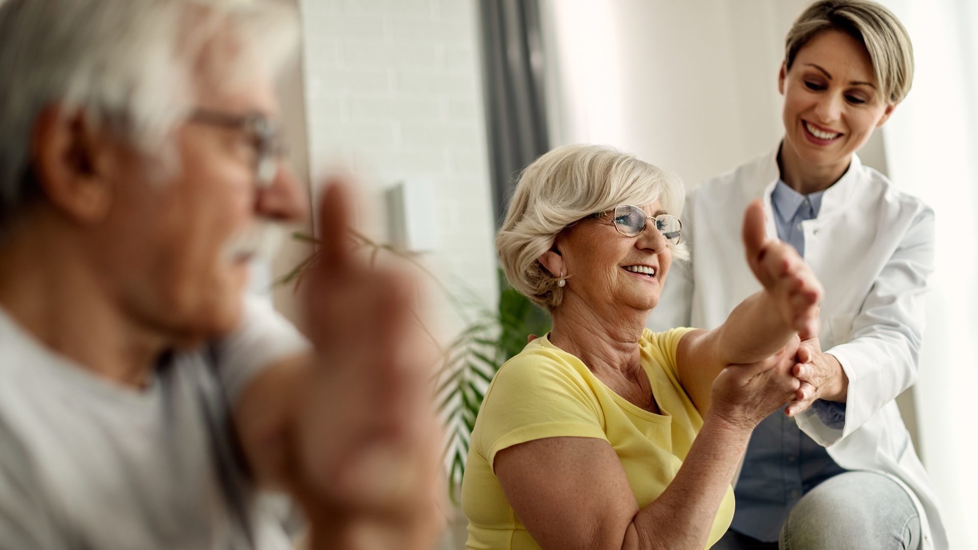 Happy physiotherapist helping to senior couple with stretching e
